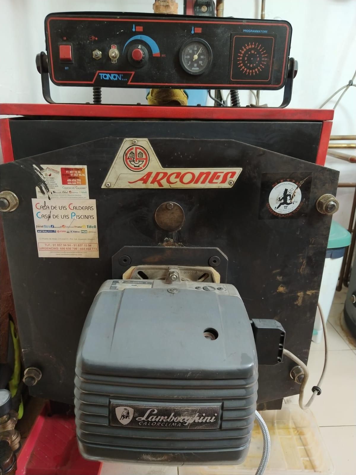 Una caldera negra y roja con un reloj encima.